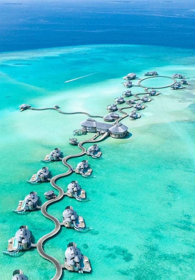 Aerial view of overwater bungalows in turquoise lagoon