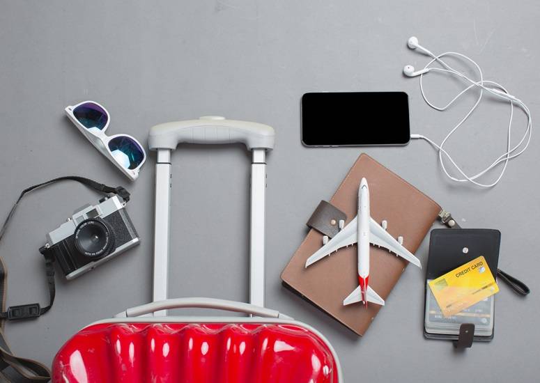 Travel flat lay with suitcase, passport, camera, and airplane model